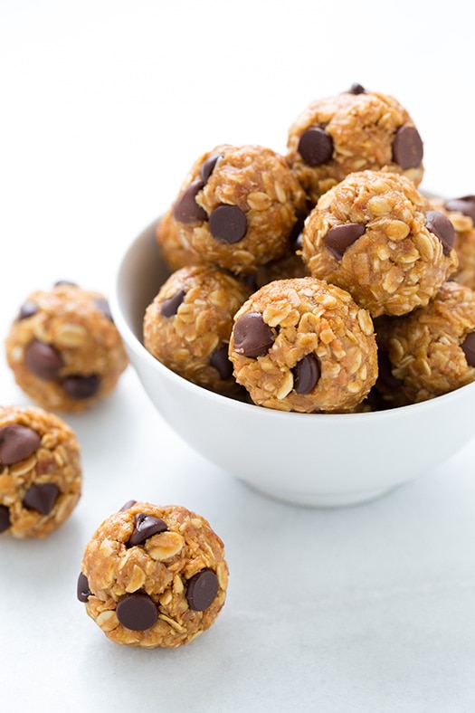 A close up of No Bake Energy Bites in a white bowl with a couple scattered beside it
