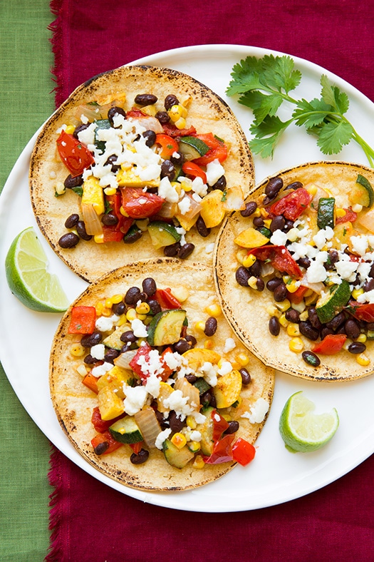 three vegetarian tacos on a white plate with lime and cilantro