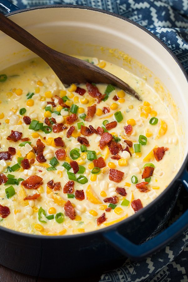 Summer Squash and Corn Chowder in a blue pot with a wooden ladle.