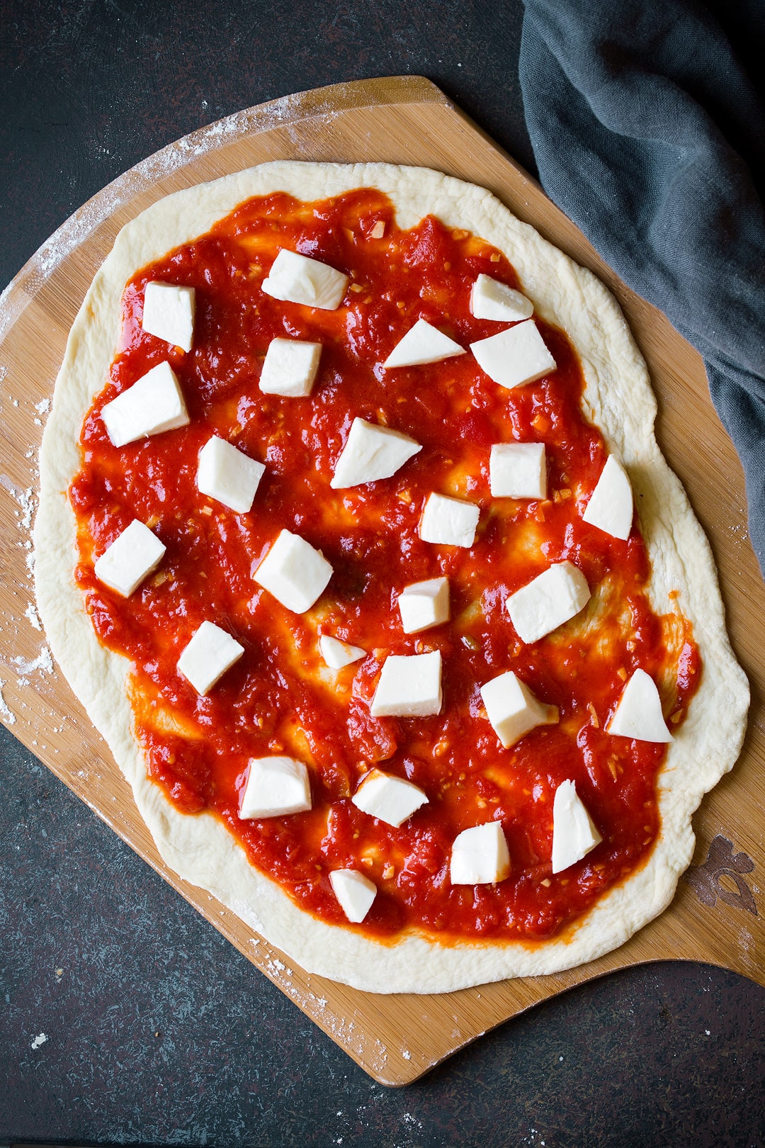 assembling a Margherita Pizza on a wood pizza peel