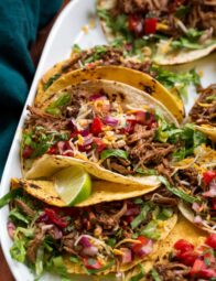Close up photo of shredded beef tacos with toppings.