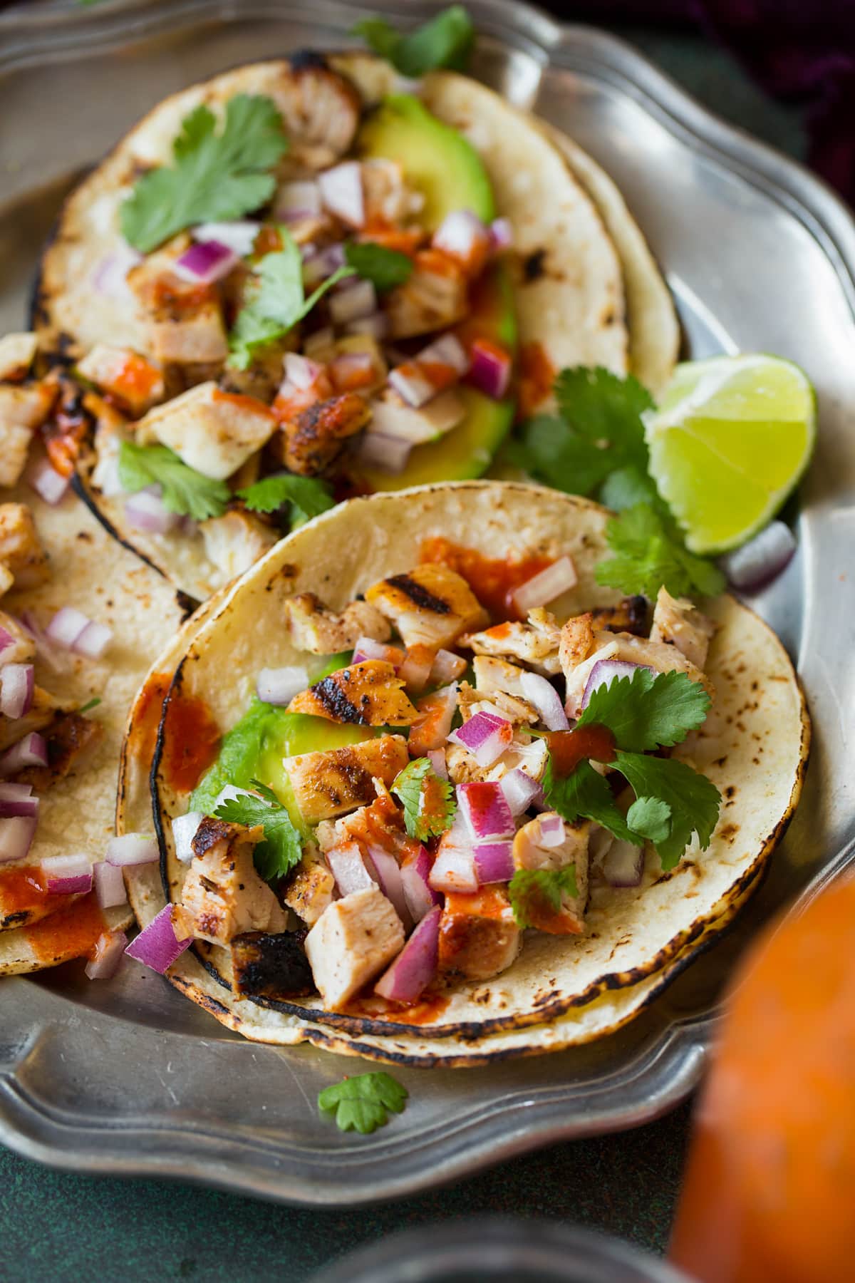 Close up image of chicken street tacos shown laying open on a serving plate.