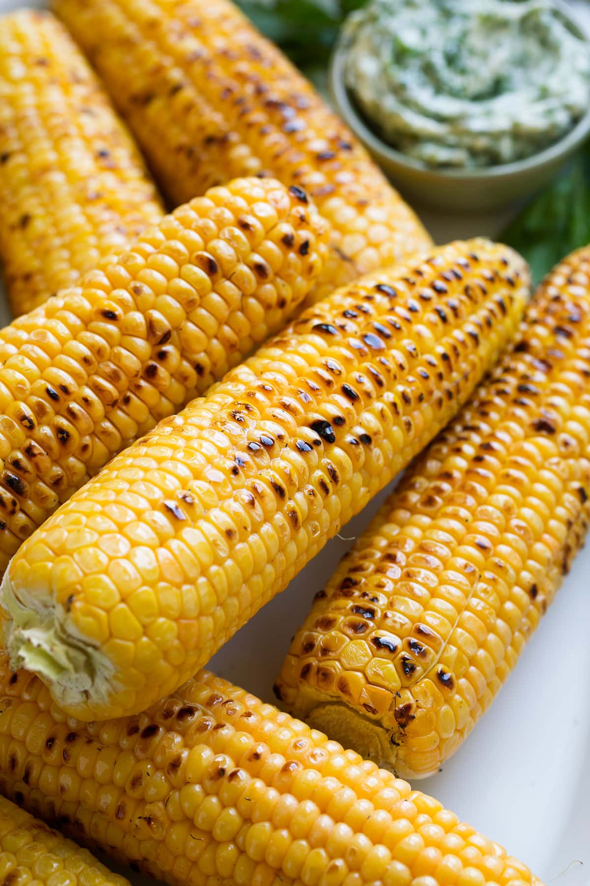 Grilled Corn on the Cob + 3 Flavored Butters Close up image of stack of grilled corn on the cob.