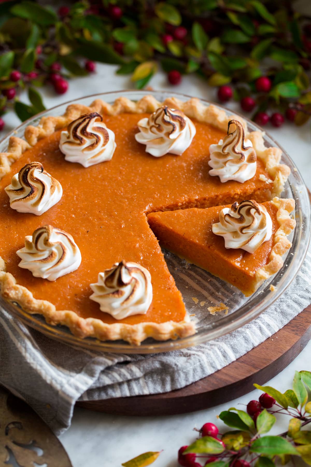 Whole sweet potato pie with a slice cut. It's topped with toasted marshmallow swirls.