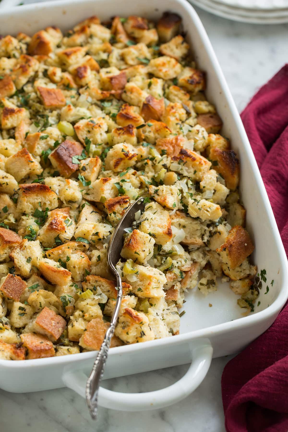 Scooping out a spoonful of stuffing in baking dish.