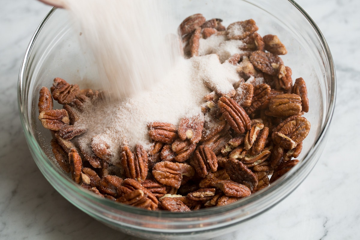 Adding sugar mixture to egg coated nuts.
