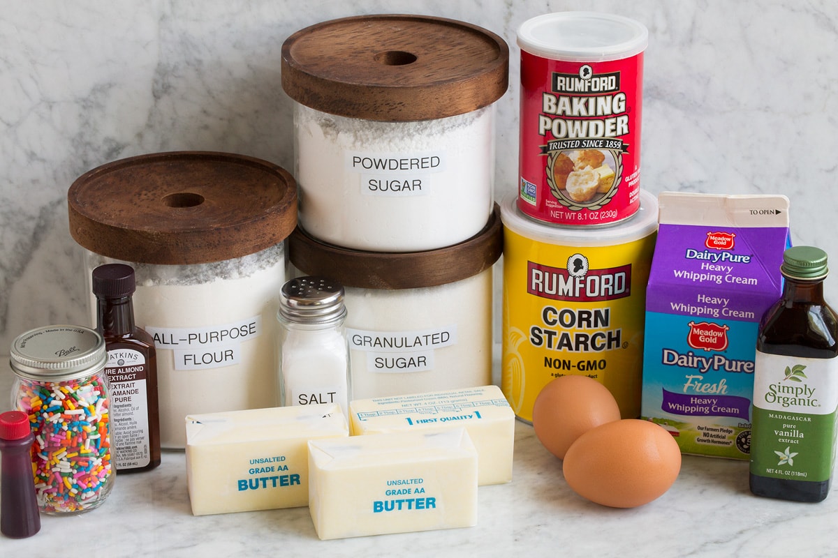 Sugar Cookie Bars Image of ingredients that are used to make sugar cookie bars. Includes flour, sugar, powdered sugar, butter, eggs, baking powder, cornstarch, cream, vanilla, almond extract, sprinkles and food coloring.