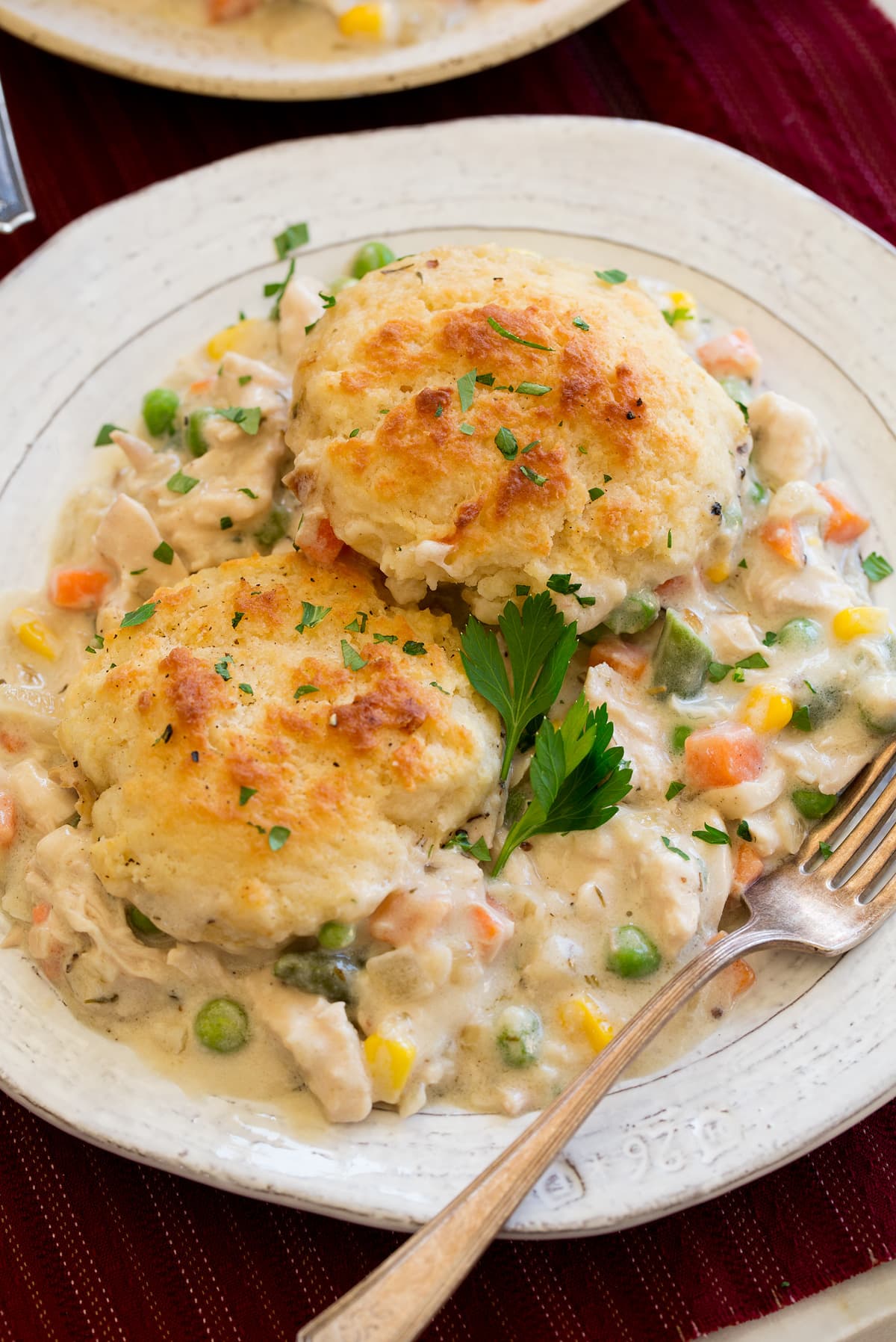 Serving of chicken and biscuit pot pie on a white plater with a fork to the side.