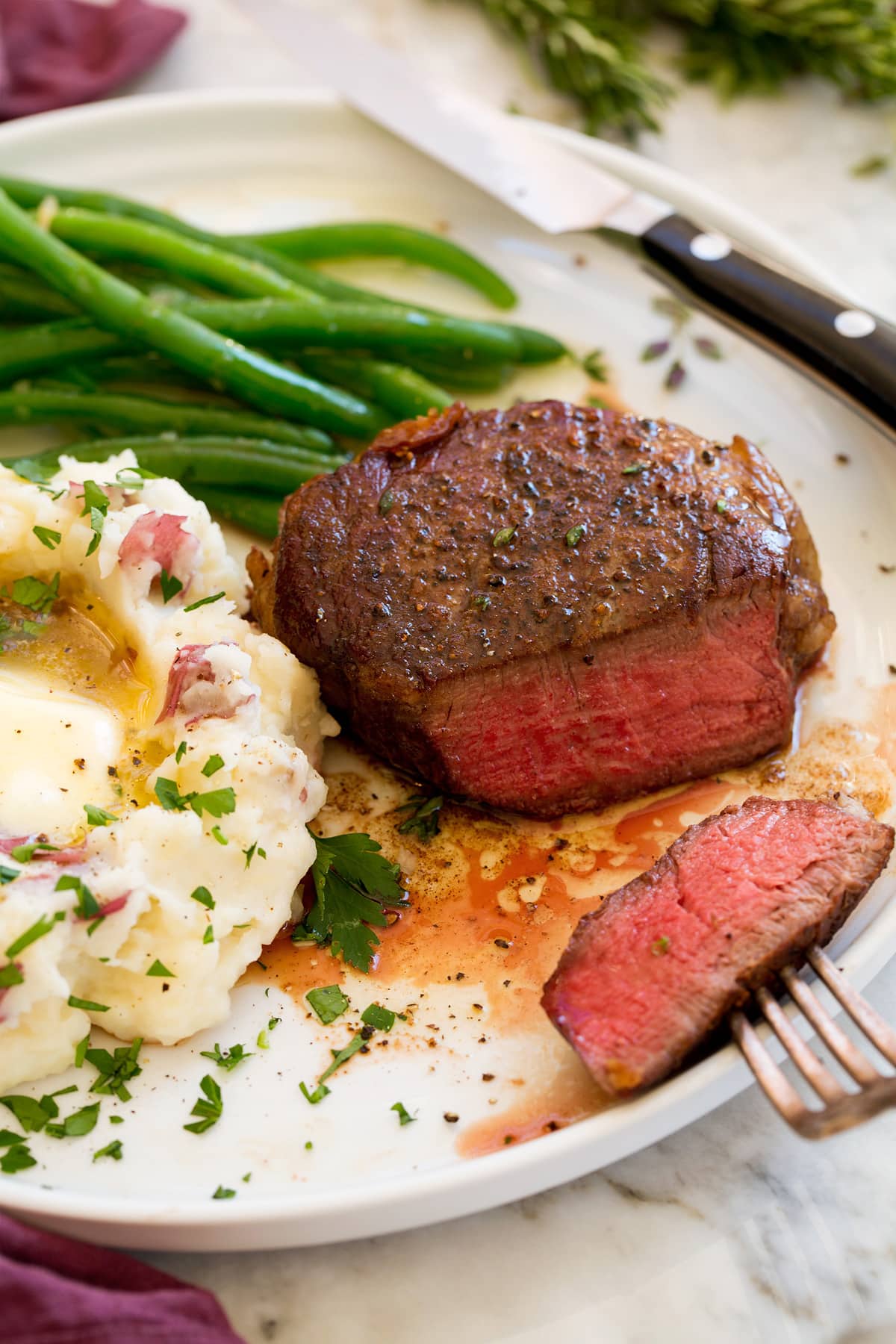 Fillet Mignon Filet Mignon shown on a serving plate with a side of mashed potatoes and steamed green beans.
