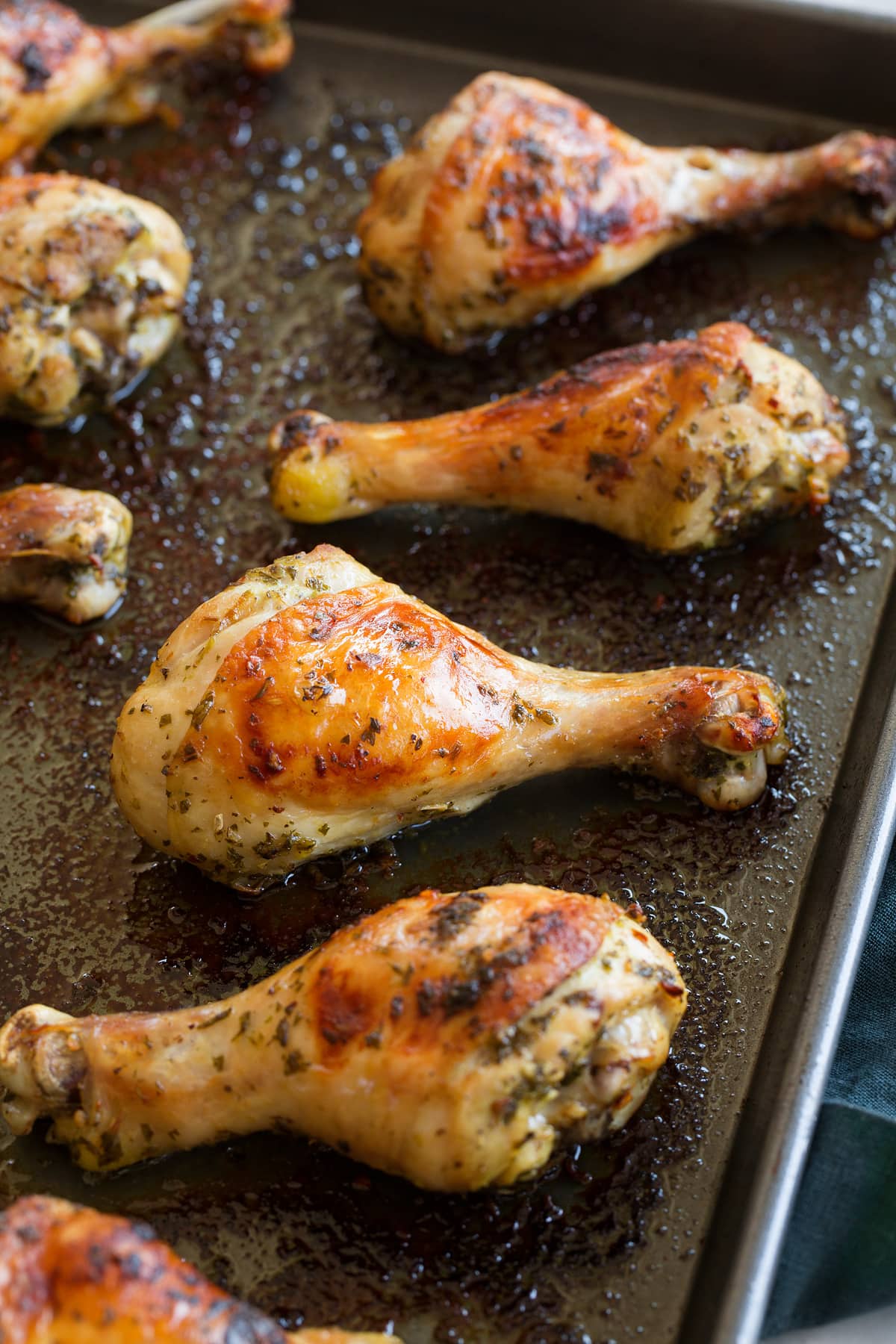 Baked Chicken Legs Close up photo of chicken drumsticks on a dark baking sheet.
