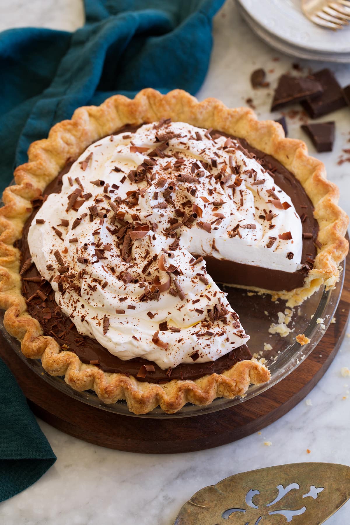 Chocolate Cream Pie Whole chocolate cream pie decorated with fluffy whipped cream and chocolate curls. One slice is cut from the pie to show the filling.