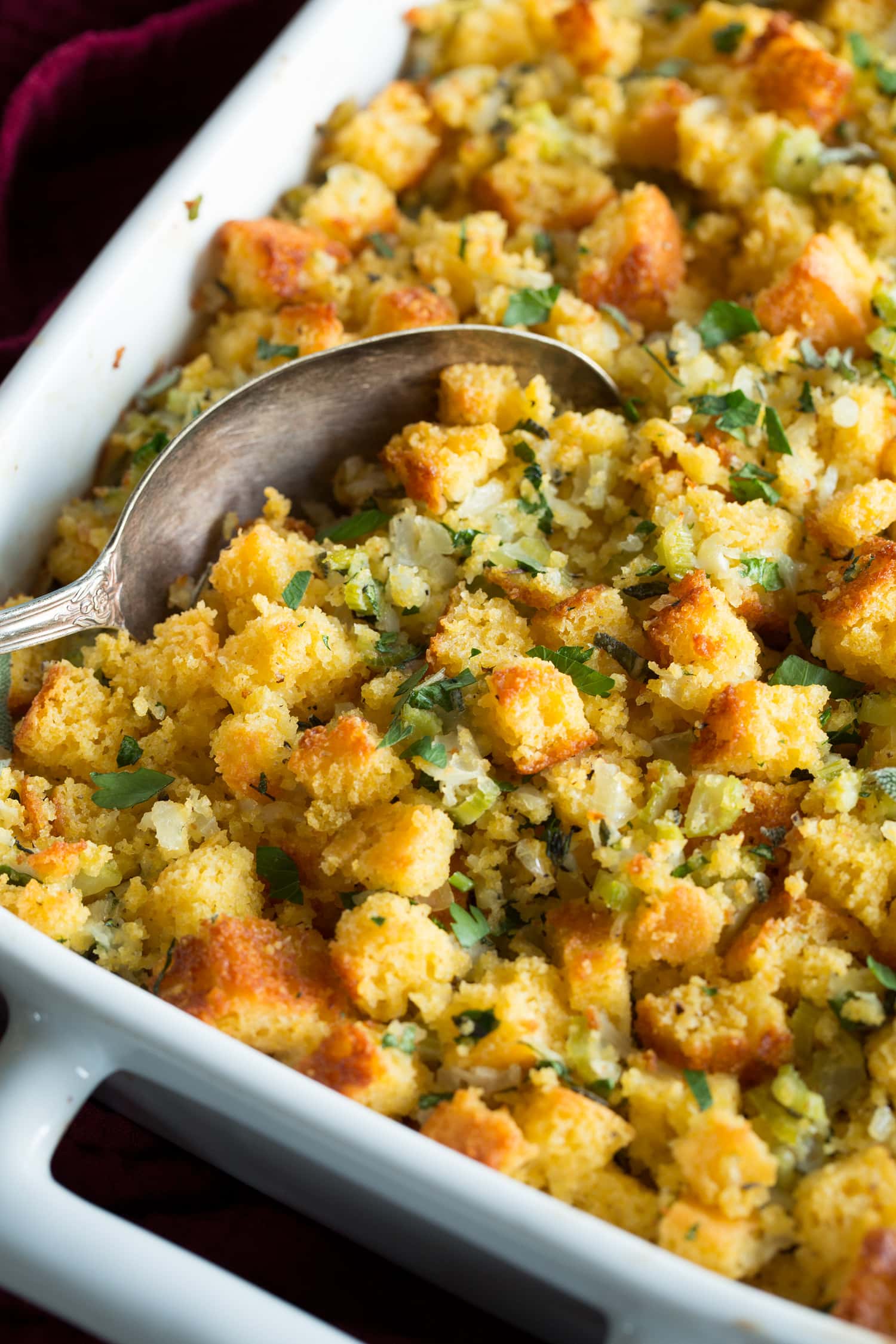 Cornbread Stuffing Close up photo showing stuffing being scooped from baking dish.