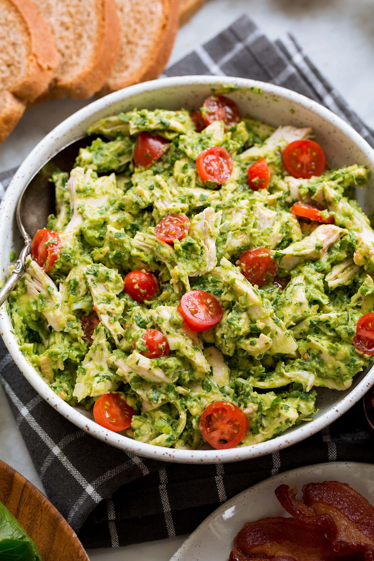 Avocado Chicken Salad Avocado chicken salad mixture in a bowl with tomatoes.