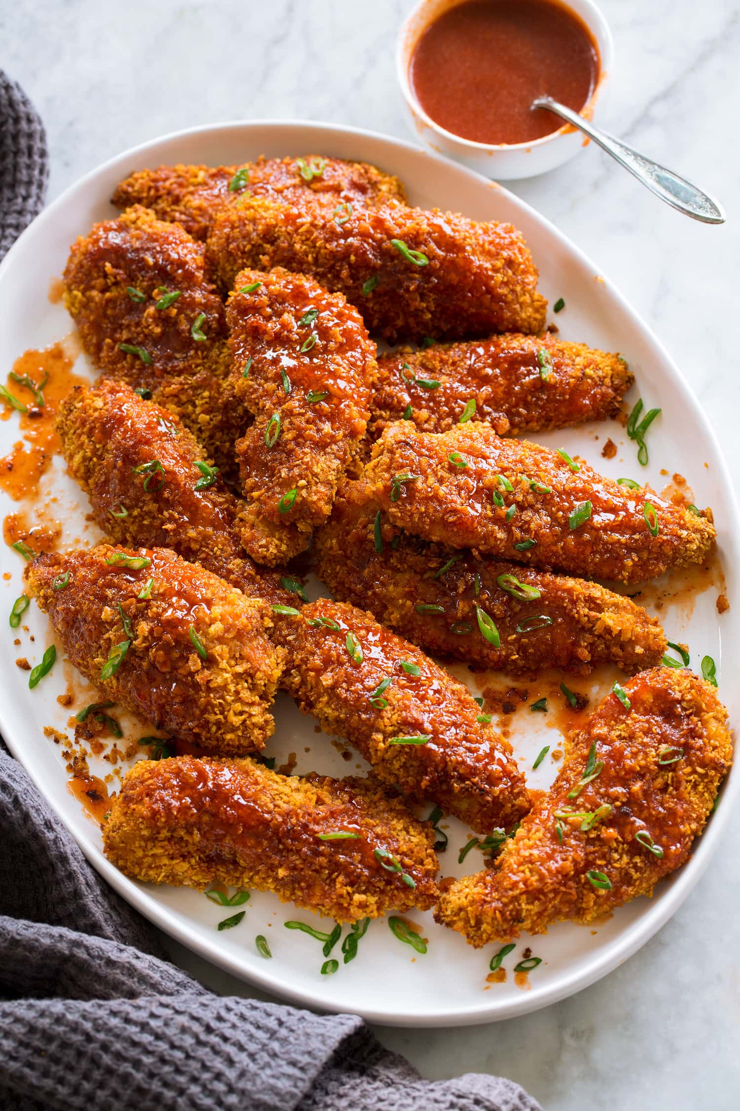 Hot Honey Chicken Hot honey chicken shown on a white oval platter garnished with green onions.