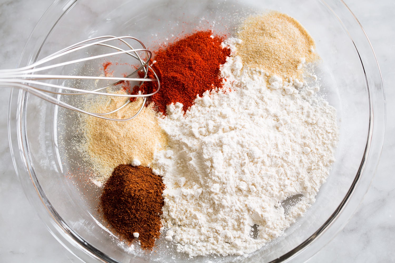 Hot Honey Chicken Mixing flour and spices in a shallow dish for dredging chicken.