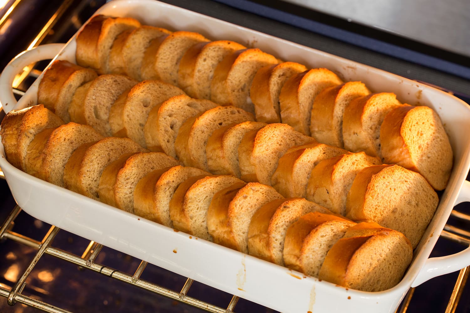 Baked French Toast French toast in rows in baking dish shown baking in the oven.