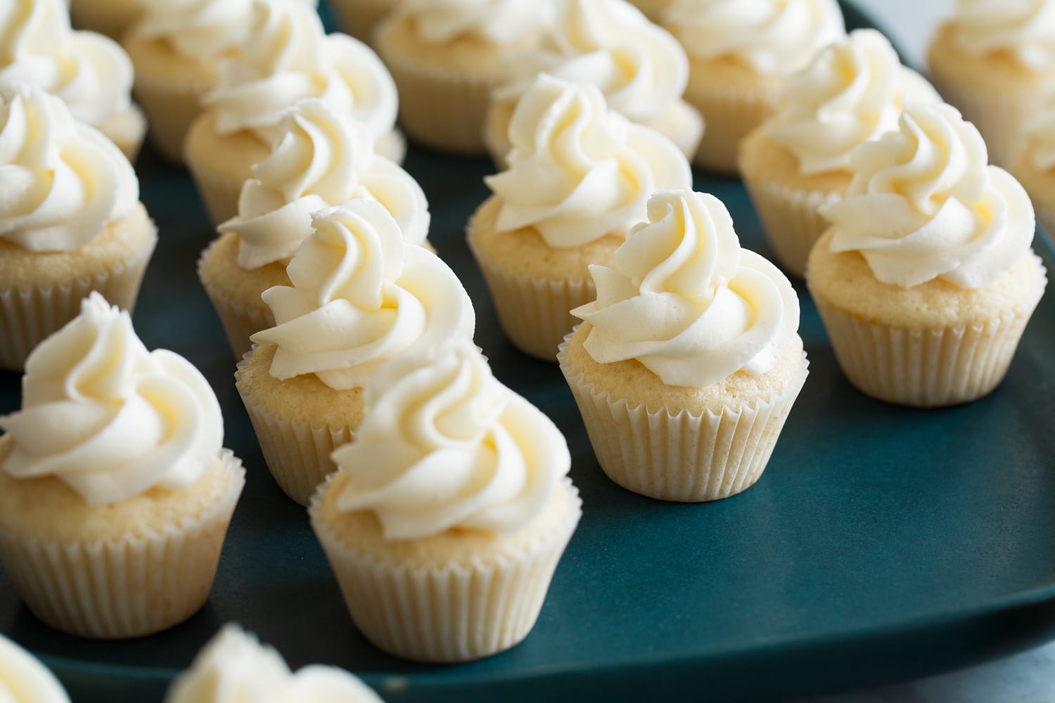 Mini Cupcakes Mini vanilla cupcakes completed with frosting on top.