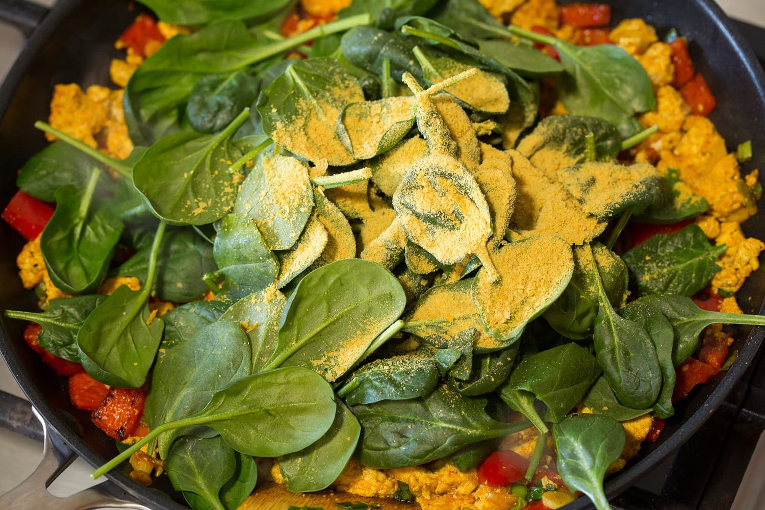 Tofu Scramble Adding spinach and nutritional yeast to skillet.