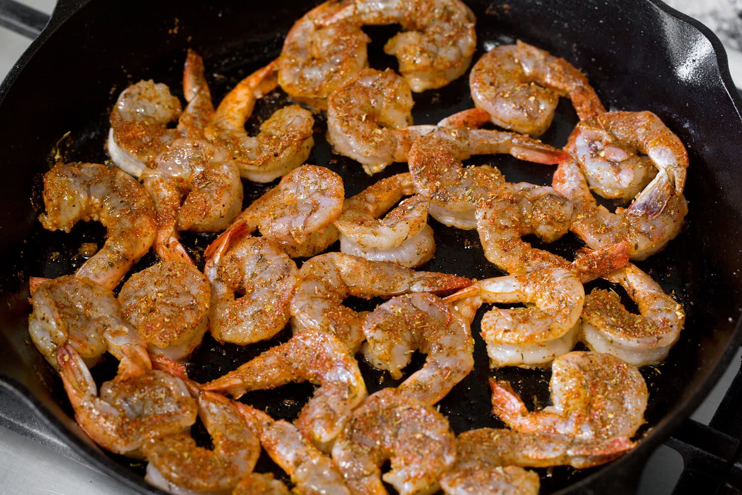 Blackened Shrimp Blackened shrimp shown cooking in a cast iron skillet on the first side.