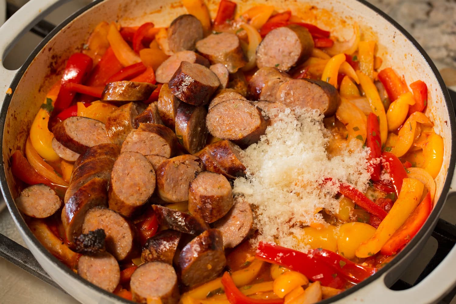 Italian Sausage Peppers and Onions Italian sausages shown sliced into coins and to pan along with parmesan as the last step.