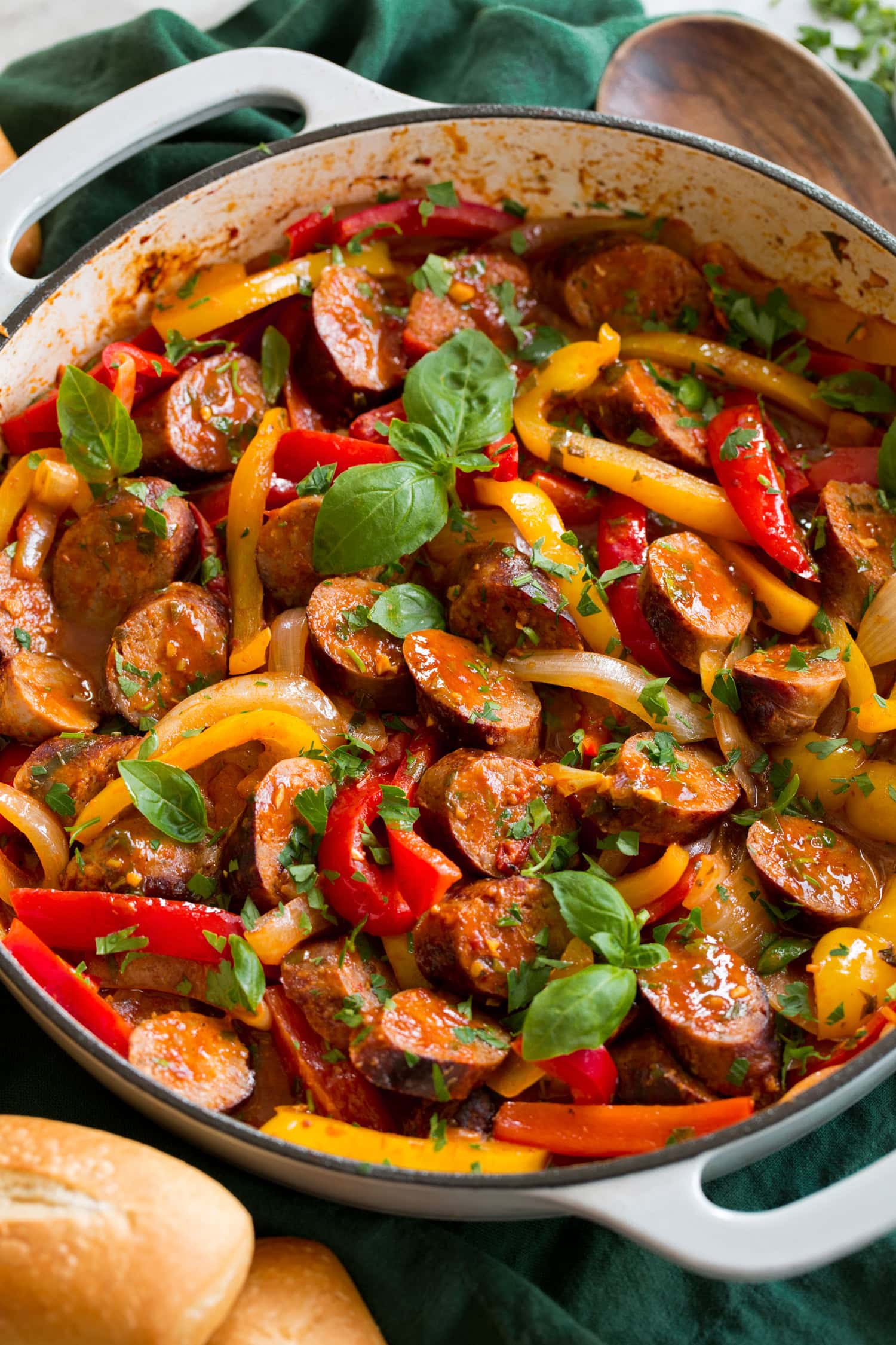 Italian Sausage Peppers and Onions Sausage, peppers and onions shown close up in a white enameled skillet.