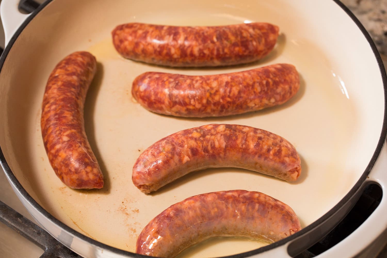 Italian Sausage Peppers and Onions Italian sausage links shown in a skillet before cooking.