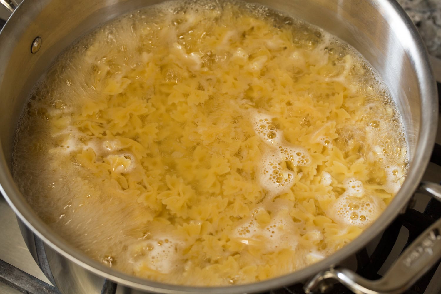 Creamy Pesto Pasta Farfalle pasta cooking in a large pot of water.
