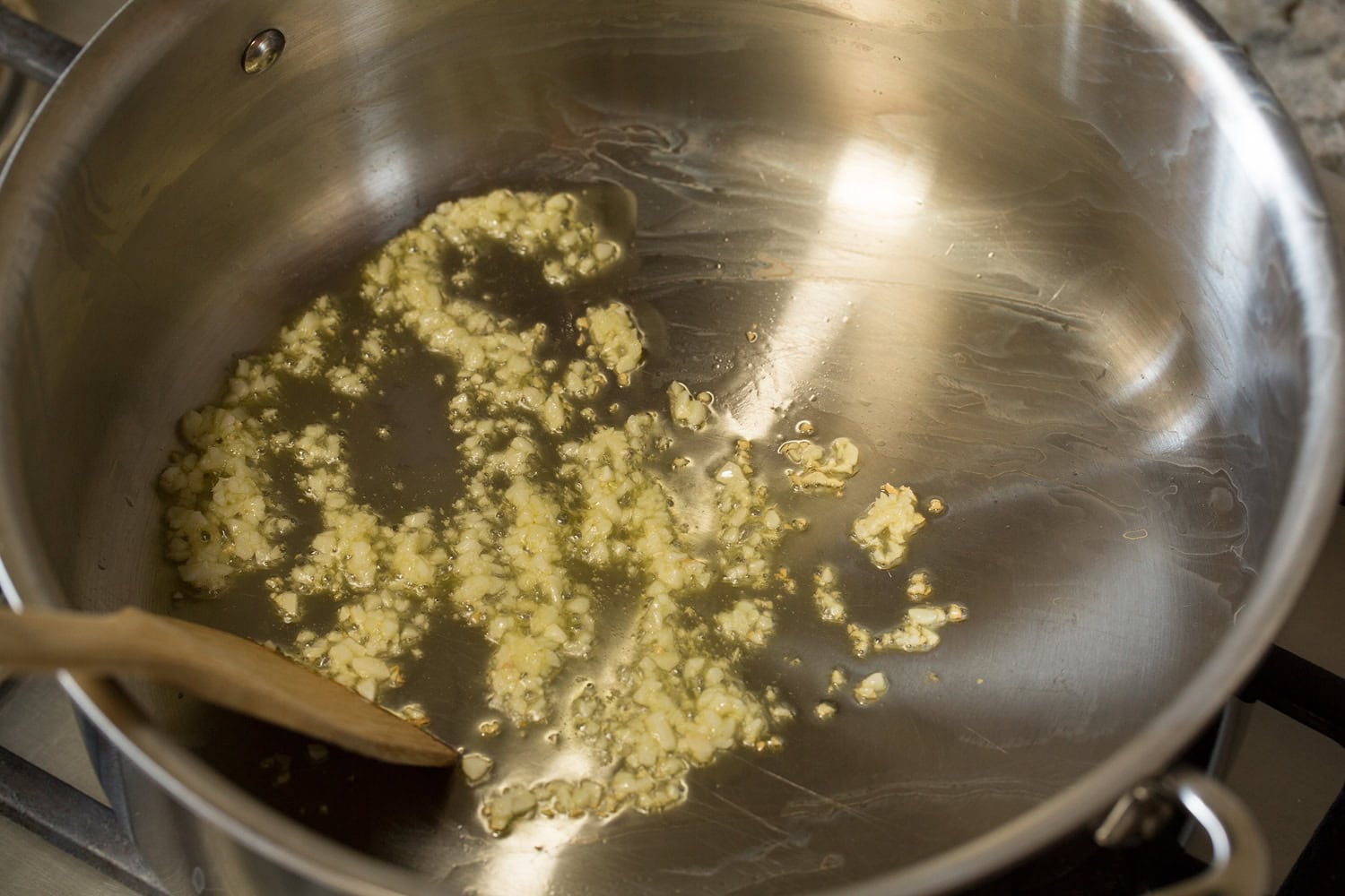 Creamy Pesto Pasta Garlic sauteing in oil in a pot.