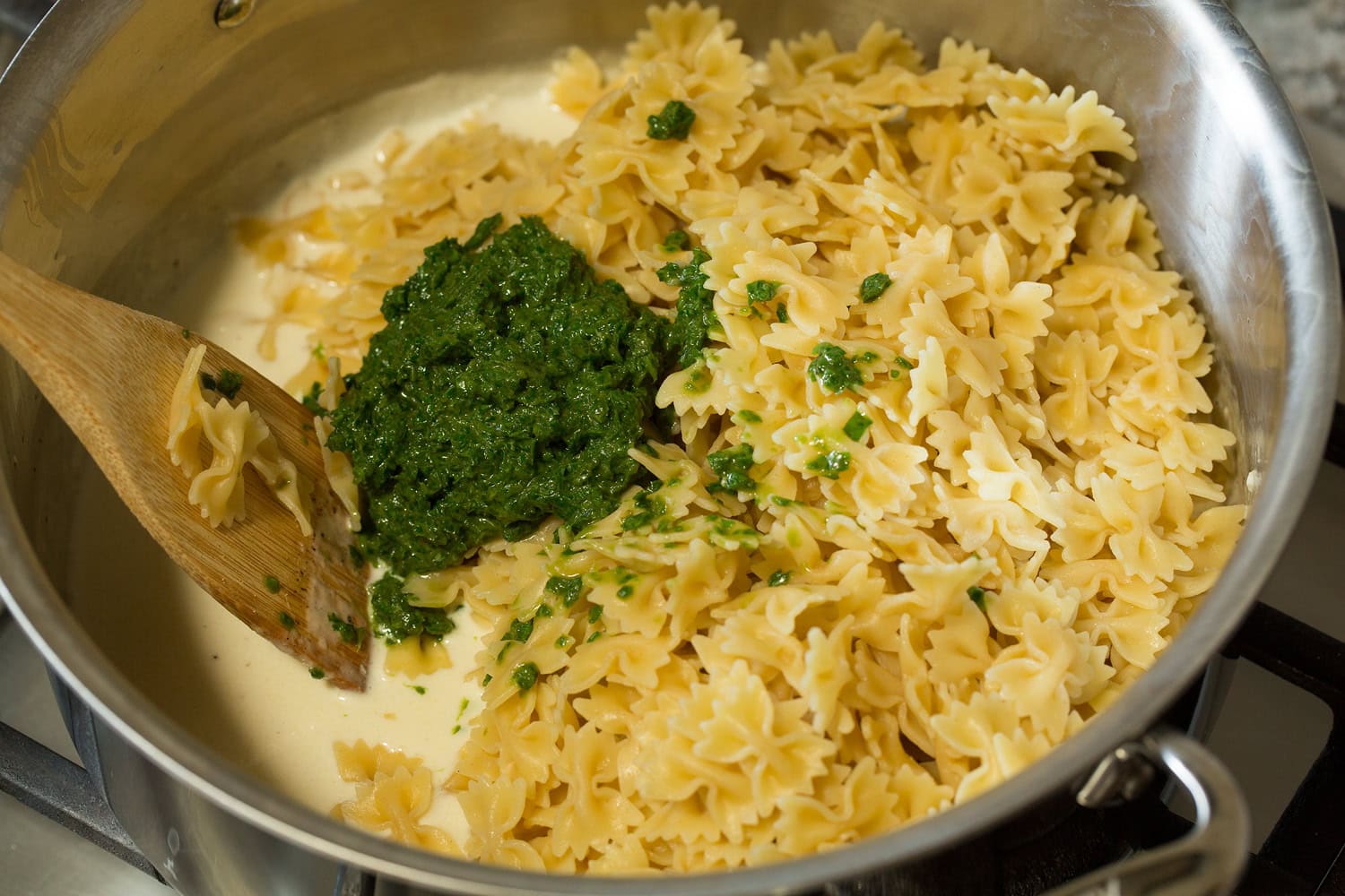 Creamy Pesto Pasta Pasta and basil mixture added to cream mixture in pot.
