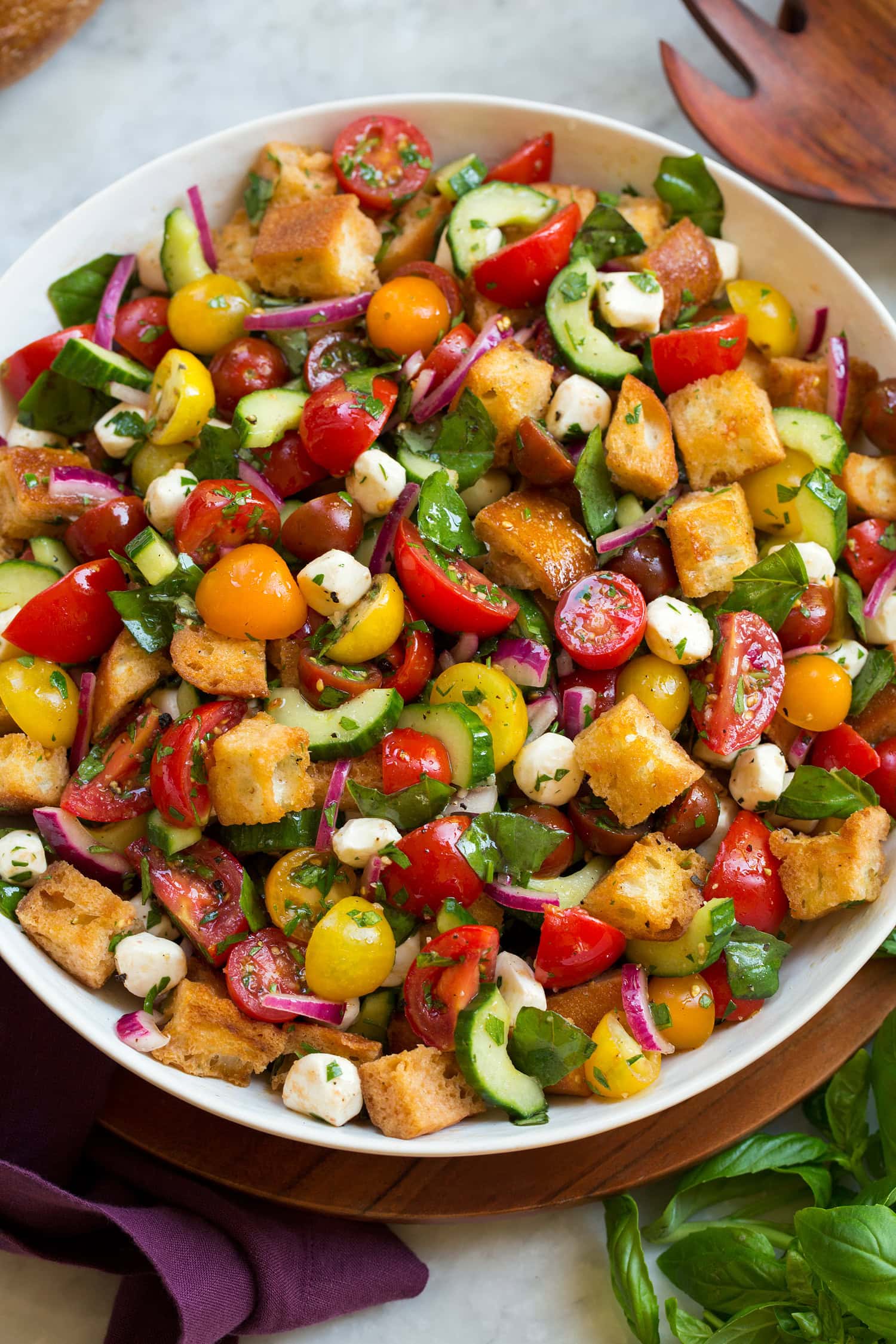 Panzanella Salad Panzanella salad made with campari tomatoes, grape tomatoes, bread, cucumbers, mozzarella, basil, red onion and parsley.