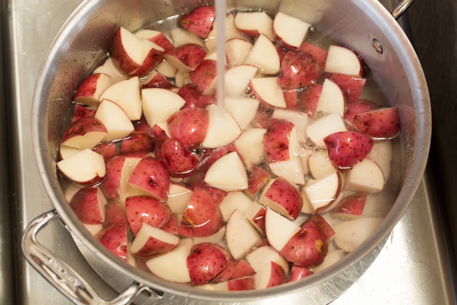 Red Potato Salad Chopped red potatoes in a pot being covered with water.
