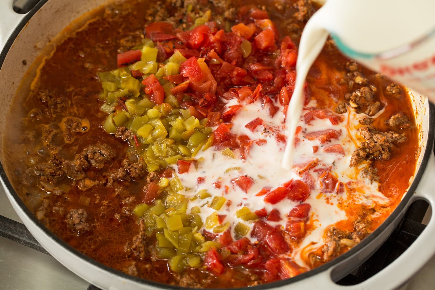 Taco Pasta Liquid, tomatoes, and green chilies added to beef in pan.