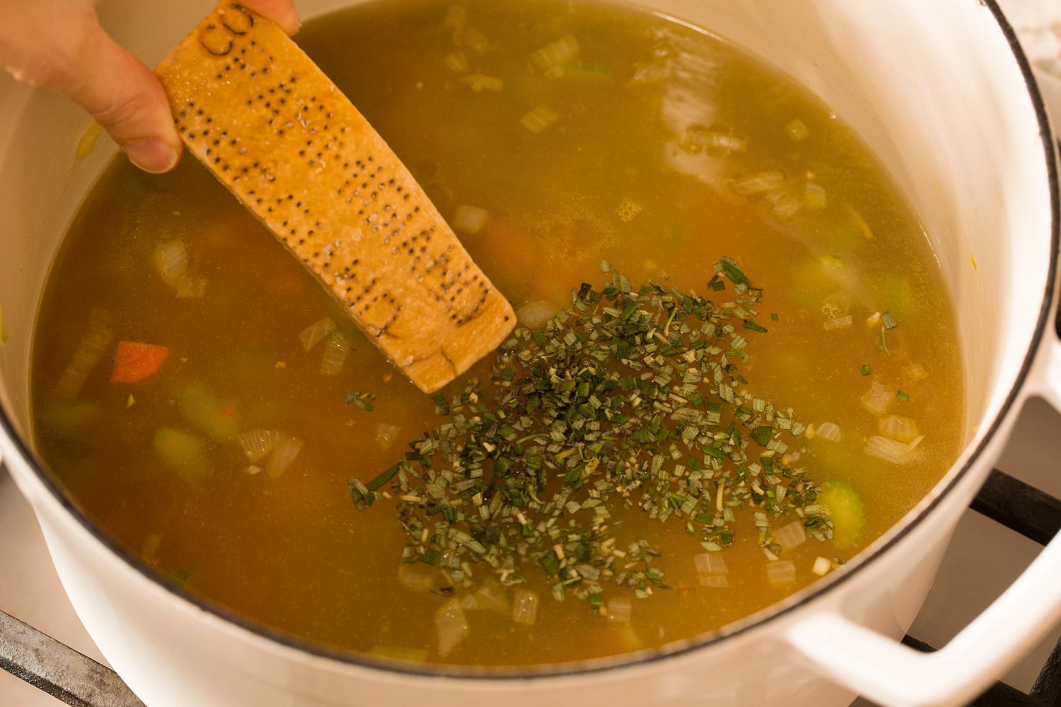 Broth, parmesan rind and herbs added to pot.