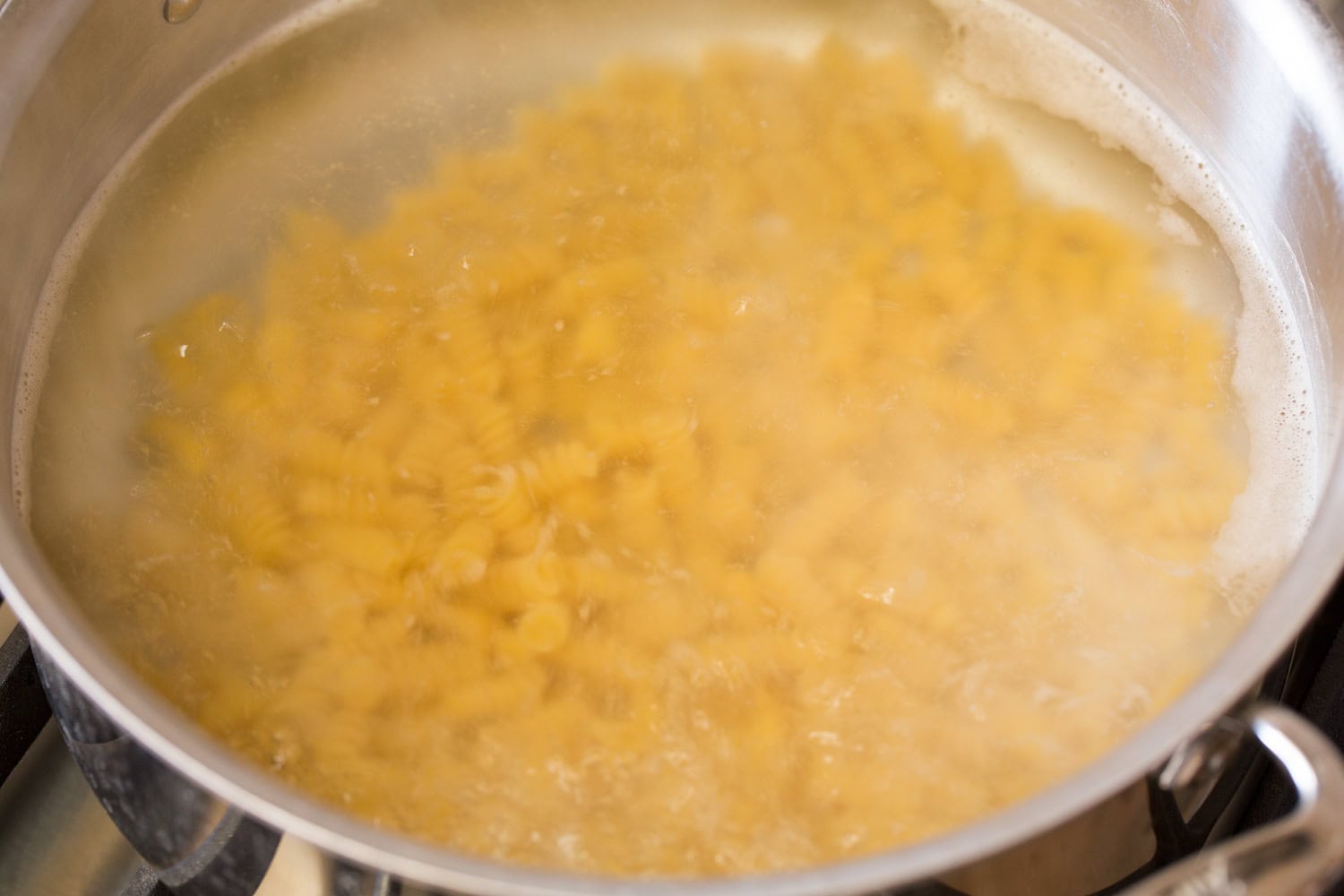 Tuna Pasta Salad Pasta boiling in a large stainless steel pot.