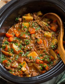 Ground beef stew with potatoes and carrots in a slow cooker.