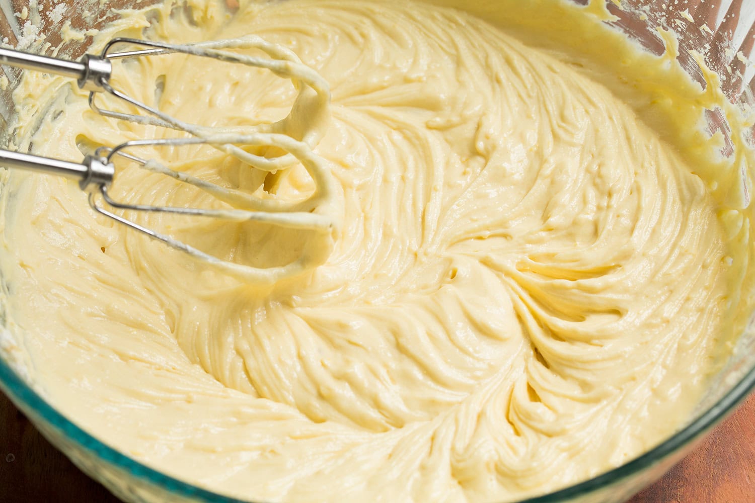 Lemon Pound Cake Completed lemon pound cake batter in glass mixing bowl with mixers in batter.