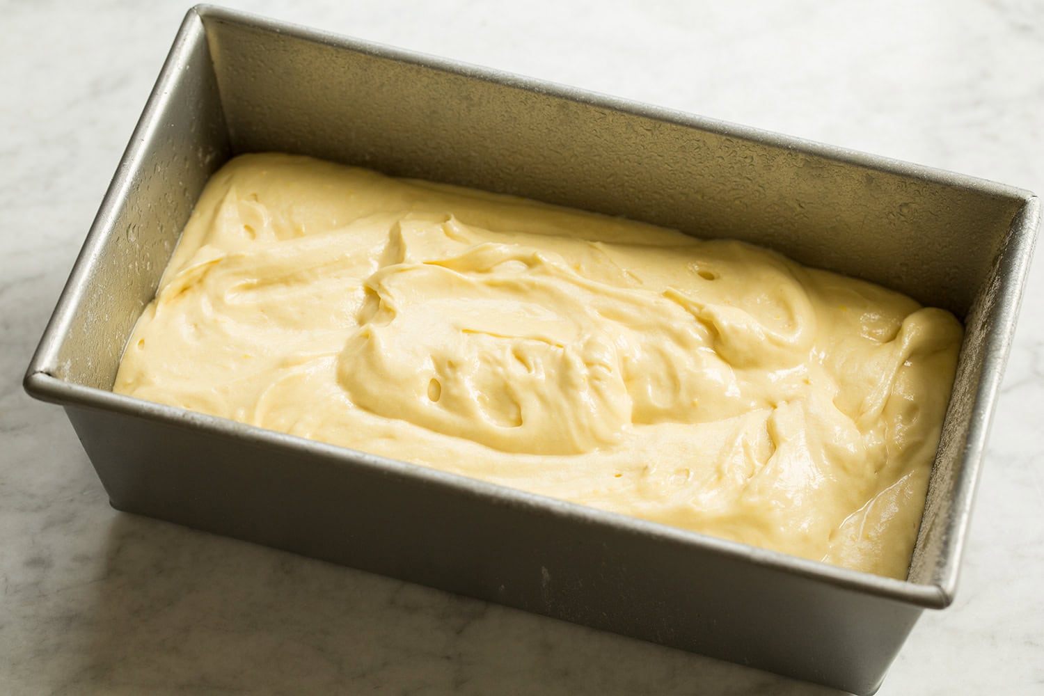 Lemon Pound Cake Lemon bread batter poured into a metal loaf pan.