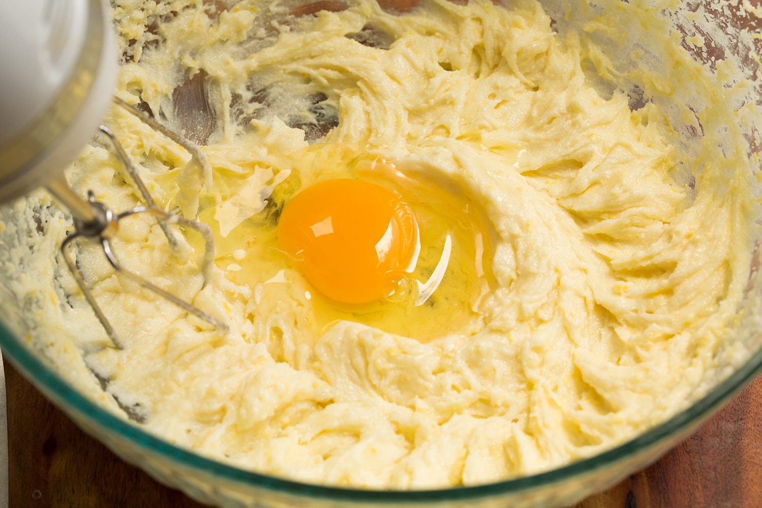 Lemon Pound Cake Egg added to butter sugar mixture in glass mixing bowl.