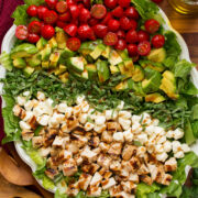 Caprese chopped salad with grilled chicken, avocado, tomato, fresh mozzarella, and basil shown from overhead.
