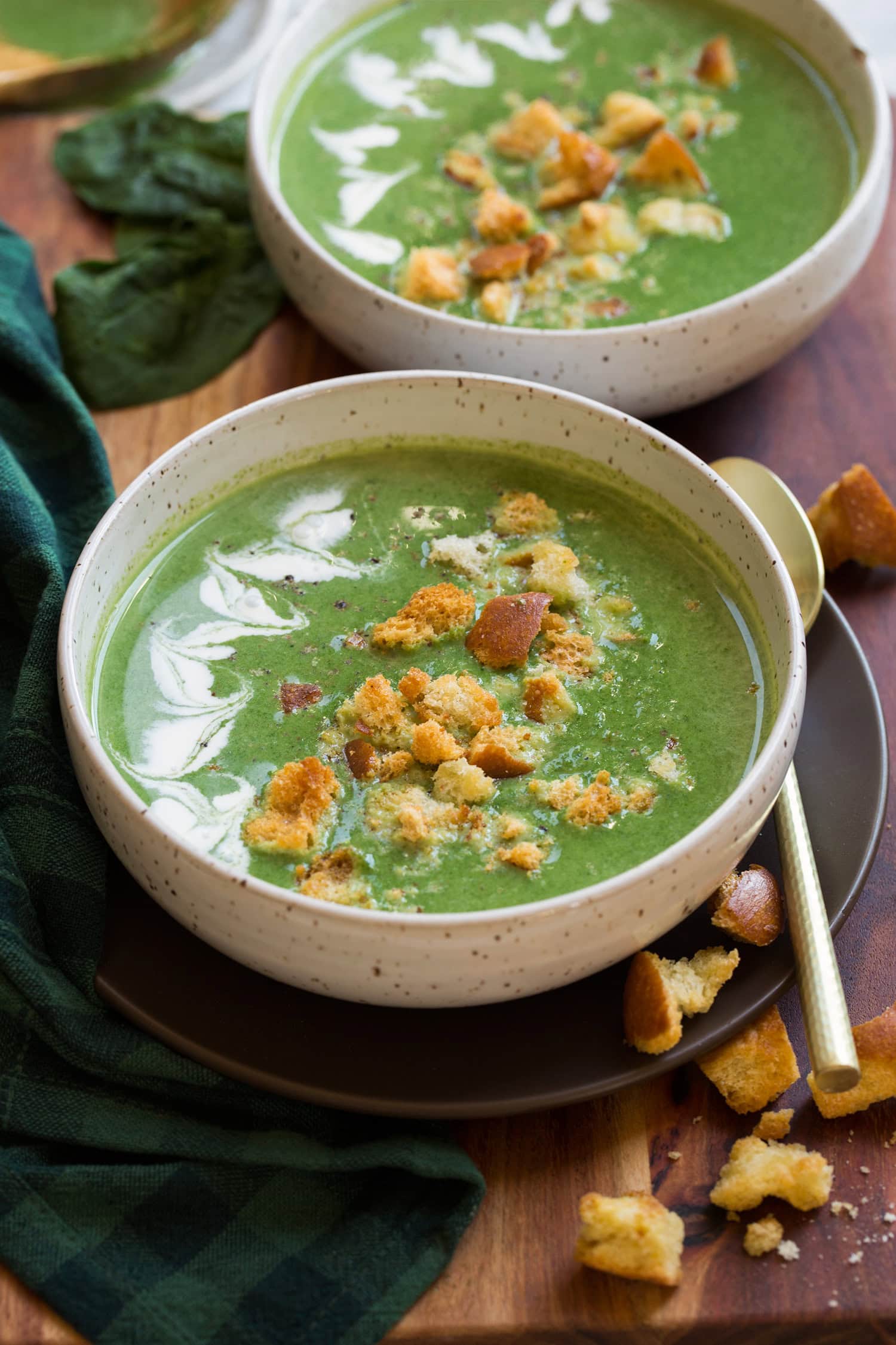 Spinach Soup Spinach soup shown with cream, homemade croutons and parmesan cheese on top. Two servings shown in white bowls.