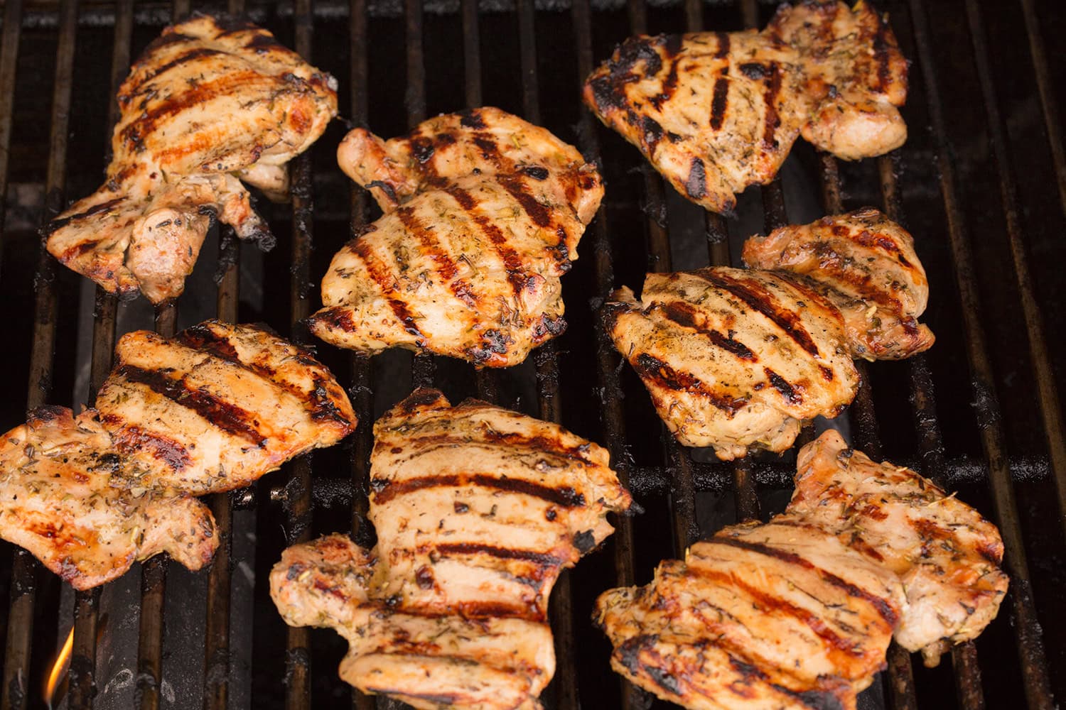 Chicken thighs shown on grill cooked through.