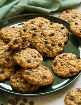 Large green plate with zucchini oatmeal chocolate chip cookies layered on it.